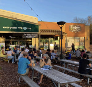 Storefront with picnic tables full of people.